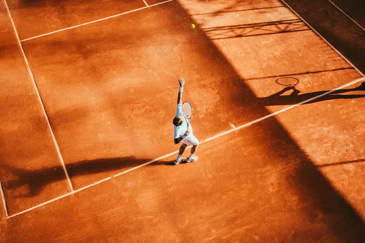 Toprak tenis kortunda raketiyle vuruş yapan sporcu